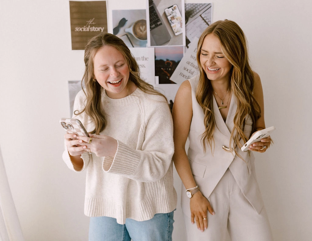 The social story team laughing in front of a photo collage